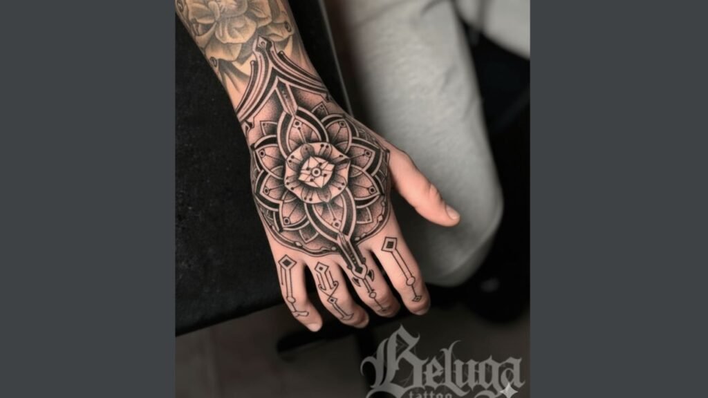 Intricate full hand tattoo on a man featuring bold skulls, lions, and geometric patterns covering the back, fingers, and sides of the hand.